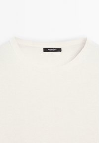 Lichtcrème gebreide trui met een ronde halslijn, ribbelranden en een small zwart label met de merknaam op de binnennaad.