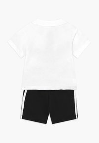 White cotton t-shirt with short sleeves and a black pair of shorts featuring white side stripes, made from soft, stretchy fabric.