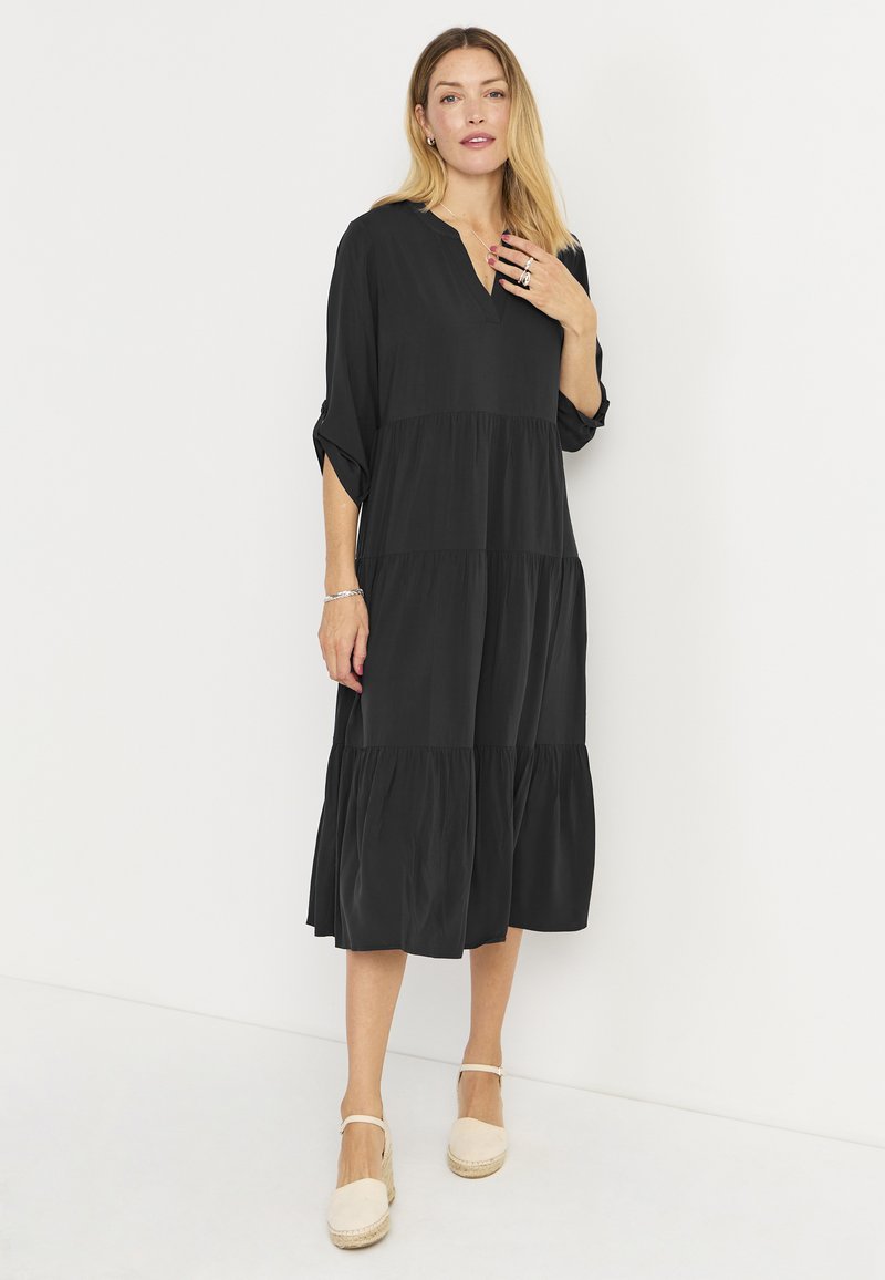 Musta kerroksittain midi-mekko V-kaula-aukolla, kolmanneksen pituisilla hihoilla ja pehmeällä tekstuurilla, täydentäen beigen espadrillot.