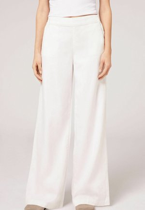 Pantalones de pierna ancha hechos de un tejido ligero en blanco, con una textura suave, bolsillos laterales y una cinturilla ajustada.
