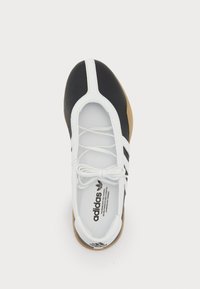 Black and white sneaker with a low profile, featuring a smooth upper, three signature stripes, round toe, and a rubber sole.