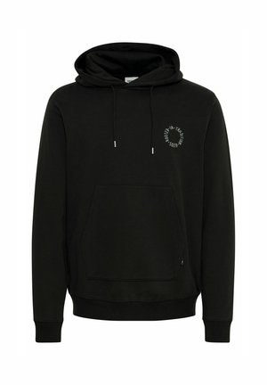 Black hoodie with front kangaroo pocket, drawstring hood, and small white circular text on left chest reading "Rooted in Tradition Solid."