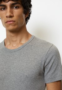 T-shirt grigio a maniche corte realizzato in un morbido tessuto testurizzato, con scollo rotondo e silhouette aderente.