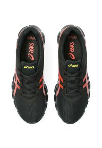 Scarpe da ginnastica nere con accenti rossi, parte superiore in rete, punta arrotondata e suola ammortizzata. Hanno un logo prominente sulla linguetta e sui lati.