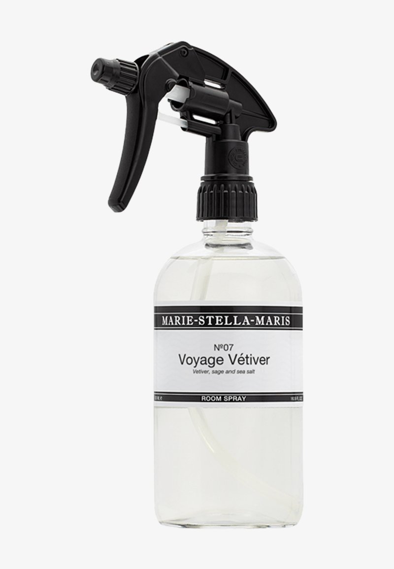 Flacone spray in vetro trasparente con trigger e tappo neri. Etichetta bianca con testo nero, che riporta "Voyage Vétiver" e le note olfattive. Capacità di 500 mL.