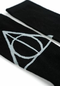 Calze nere lavorate a maglia con un design geometrico grigio chiaro, che comprende un cerchio e un triangolo, con una texture morbida e una vestibilità aderente.