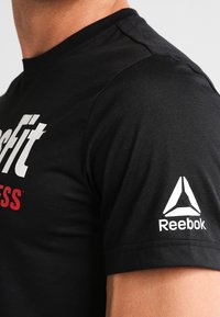 Černé tričko s krátkým rukávem s nápisem "CrossFit" v bílé a červené barvě; logo Reebok v bílé barvě na levém rukávu; vyrobeno z hladkého materiálu.