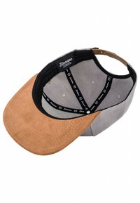 Gorra de béisbol con visera de ante marrón y cuerpo de algodón gris; presenta una banda interior negra con logo y seis orificios de ventilación.