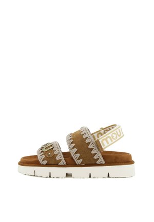 Bruine suède sandaal met twee gestikte bandjes, een witte elastische achterband met "mou" merkopdruk en een dikke witte rubberen zool.