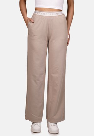 Pantaloni felpa beige in cotone con design a gamba larga, vita elastica con logo e tasche laterali. Texture liscia, stile casual.