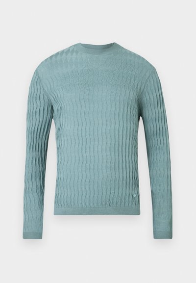 Ανοιχτό μπλε πουλόβερ από απαλό ύφασμα, με υφασμένο κυματιστό μοτίβο, μακριά μανίκια και στρογγυλή λαιμόκοψη. Χωρίς εμφανή μεταλλικά στοιχεία ή διακοσμητικά.