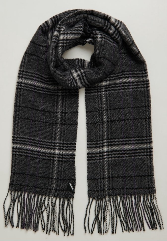 Écharpe en laine gris foncé à motif à carreaux noirs et blancs avec des extrémités effilochées, pliée en boucle vers le haut.