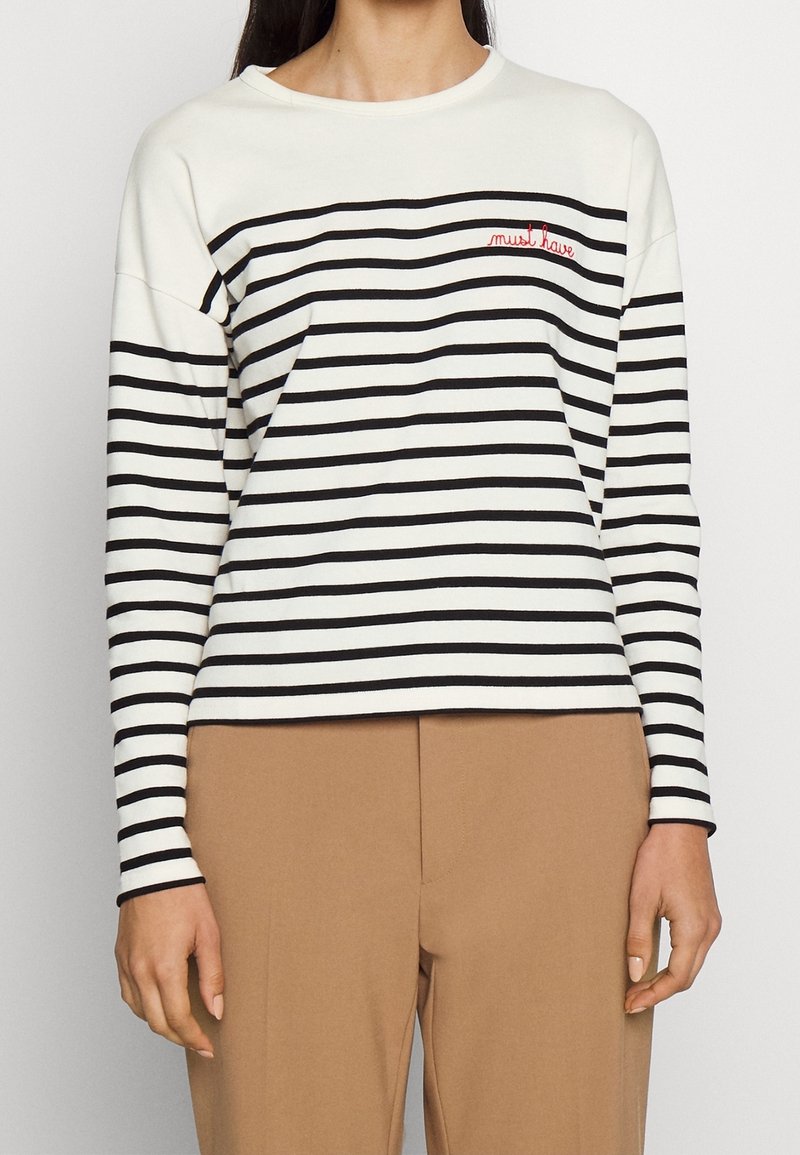 Långärmad randig topp i vitt och svart med en figurnära design. Har en röd broderad "måste ha" text på bröstet. Mjuk tyg.