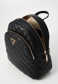 Sac à dos matelassé noir en cuir, doté de quincaillerie dorée, de deux compartiments zippés et d'une poignée supérieure pour un transport facile.