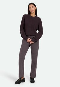 Dark purple ribbed sweater with long sleeves, paired with gray straight-leg trousers and black chunky loafers featuring gold accents.