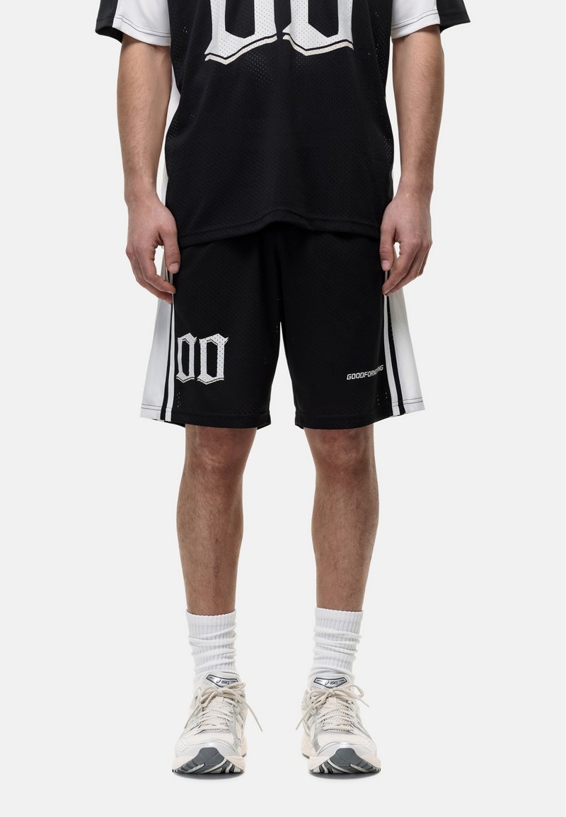 Zwart mesh basketbal jersey en shorts set met witte accenten, voorzien van grote cijfers en zijstrepen. Draag het met lichtgekleurde sneakers.