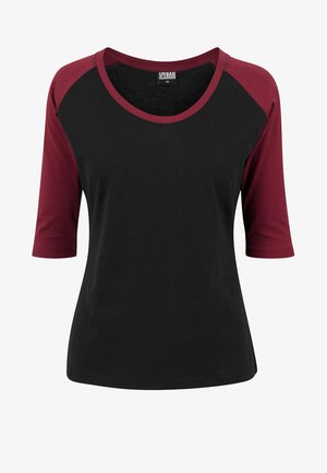 Musta ja burgundivärine raglan-t-särk, millel on ümar kaelus ja kolmveerandvarrukad, valmistatud pehmest materjalist. Urban Classics bränding nähtav seest.