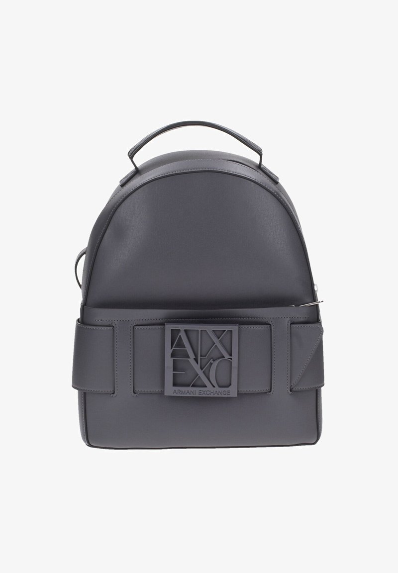 Sac à dos en cuir gris avec un haut arrondi, une base plate, des bretelles réglables et un grand patch logo à l'avant, avec une texture lisse.