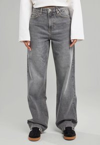 Jeans de tiro alto y pierna ancha en denim gris desgastado, con un sutil efecto de lavado, que cuentan con un diseño clásico de cinco bolsillos y herrajes metálicos.