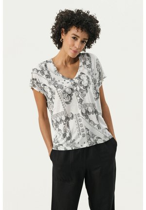 Witte T-shirt met zwart paisleypatroon, V-hals, korte mouwen en een relaxte pasvorm. Gecombineerd met losse zwarte broek.