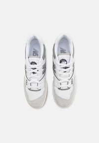 White and gray athletic shoes with a mesh and suede upper, featuring laces, a padded collar, and a prominent logo on the tongue.