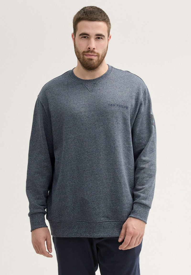 Donkerblauwe sweatshirt met lange mouwen, ronde hals en textuurstof. Heeft een klein logo op de borst en ribgebreide manchetten.