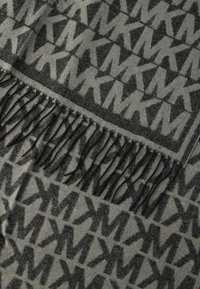 Eșarfă gri cu un model întreg negru de tip logo. Marginită cu o linie de ciucuri negri pentru textură suplimentară. Material moale țesut.