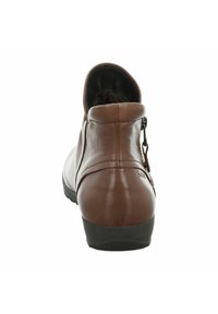 Stivaletto in pelle marrone con una finitura liscia, punta arrotondata e un piccolo dettaglio con zip sul retro. Suola in gomma nera visibile nella parte inferiore.