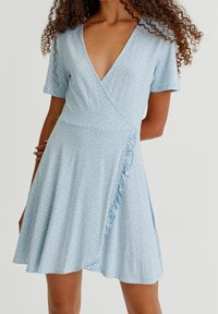 Vestido envolvente azul con estampado floral, mangas cortas, escote en V profundo, detalles de volantes y falda acampanada, hecho de tela ligera.