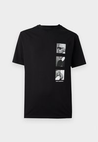 Fekete pamut póló, amely három monokróm portrét ábrázol, alján a "KARL LAGERFELD" felirattal. Rövid ujjú, kerek nyakú.