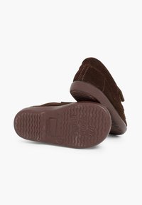 Scarpe in camoscio marrone con suola in gomma testurizzata, caratterizzate da un design semplice e da una cintura regolabile. La suola presenta un motivo ondulato per garantire aderenza.
