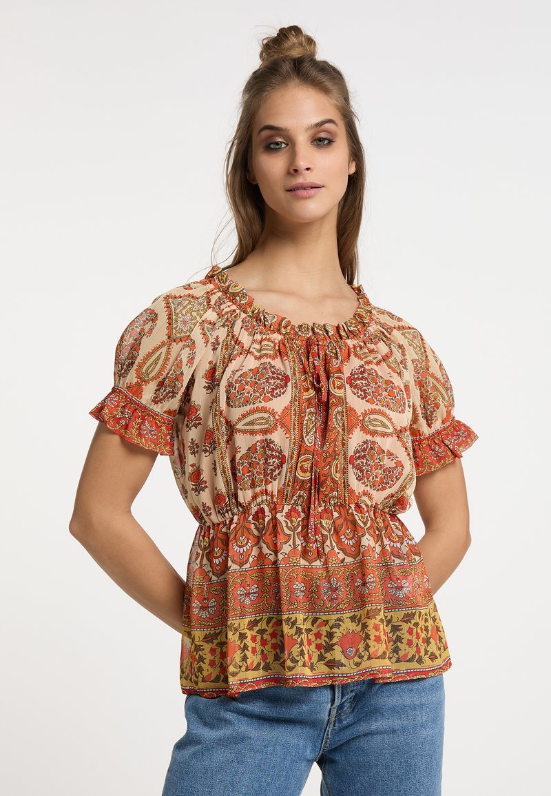 Blusa marrone con stampa floreale, colletto arricciato, maniche corte a sbuffo e vita stretta; il tessuto è leggero e testurizzato.