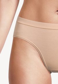 Mutande di cotone beige con una trama liscia, cintura elastica e bordi senza cuciture, viste di lato. Design semplice per il comfort.