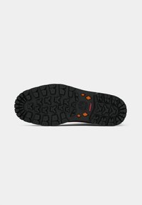 Black rugged boot sole with deep treads, orange diamond-shaped accents, and a tree logo near the center on a white background.