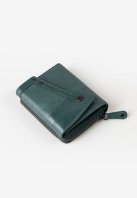 Portafoglio in pelle verde con bordo zip, chiusura a scatto e design della patta inclinato. Presenta cuciture visibili e un anello di attacco sicuro.