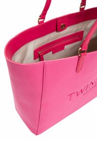 Borsa in tela rosa con dettagli in pelle, dotata di una tasca interna con zip e logo. Forma arrotondata con doppi manici.