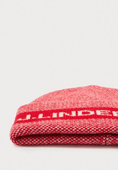 Gorro de lana rojo con un dobladillo, que presenta un patrón de rayas blancas y un diseño de texto. Textura suave, parte superior redondeada y material duradero.
