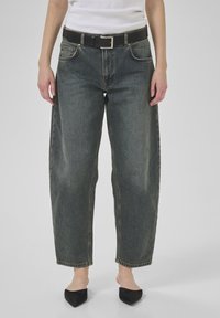 Tumši džinsu auduma platā kāju bikses ar izbalējušu apdari, ar melnu ādas jostu un kvadrātisku metāla sprādzi. Gluda tekstūra un strukturēta forma.