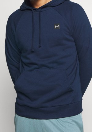 Tummansininen vetoketjullinen huppari, joka on valmistettu pehmeästä kankaasta. Hupparissa on kengurun tasku, säädettävä nyöri huoodissa ja pieni logo-ompelu rinnassa.