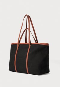 Zwarte canvas tote bag met twee bruine leren handvaten, met een gestructureerde vorm en gouden hardware accenten.