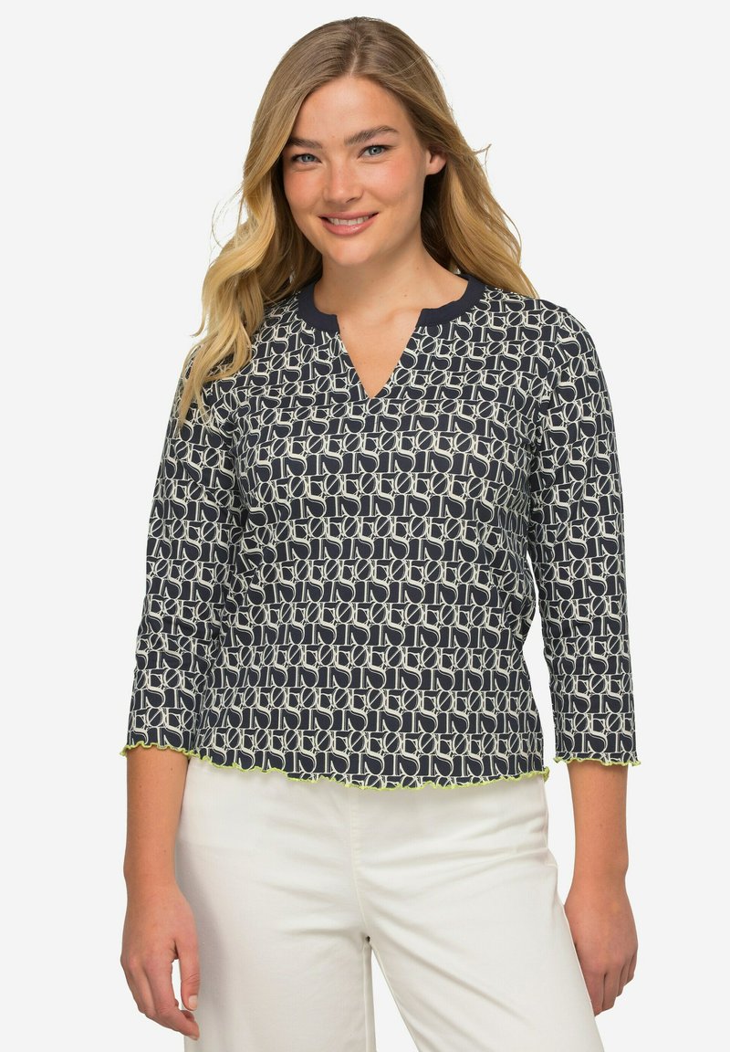 Blusa navy con un motivo geometrico crema, scollo a V, maniche a tre quarti e orlo verde lime con scallop. Tessuto leggero con una texture liscia.