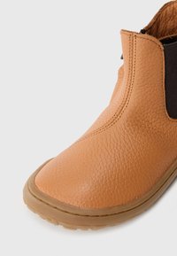 Bruine leren enkelboot met een gestructureerde afwerking, elastische zijpaneel en een rubberen zool. Heeft een ronde neus en een low-profile ontwerp.