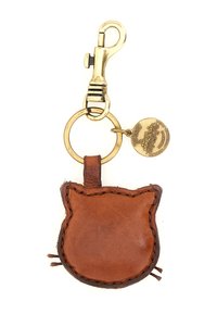 Portachiavi in pelle marrone a forma di testa di gatto, con bordi cuciti e clip in ottone con un ciondolo circolare attaccato.