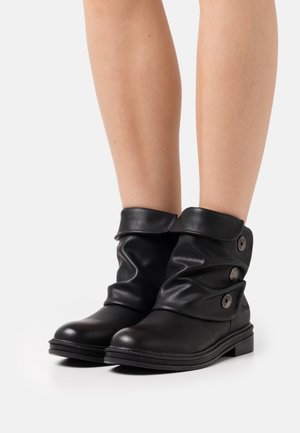 Bottes de cheville en cuir noir au design décontracté, avec trois boutons décoratifs sur le côté et une semelle plate pour le confort.