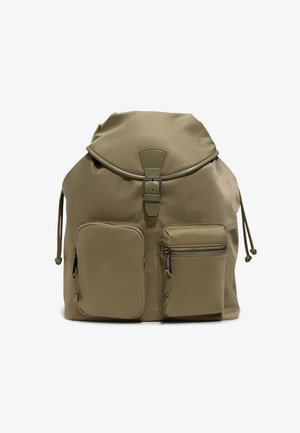 Mochila verde oliva con solapa y cierre de hebilla, dos bolsillos frontales con cremallera y lados ajustables con cordón.