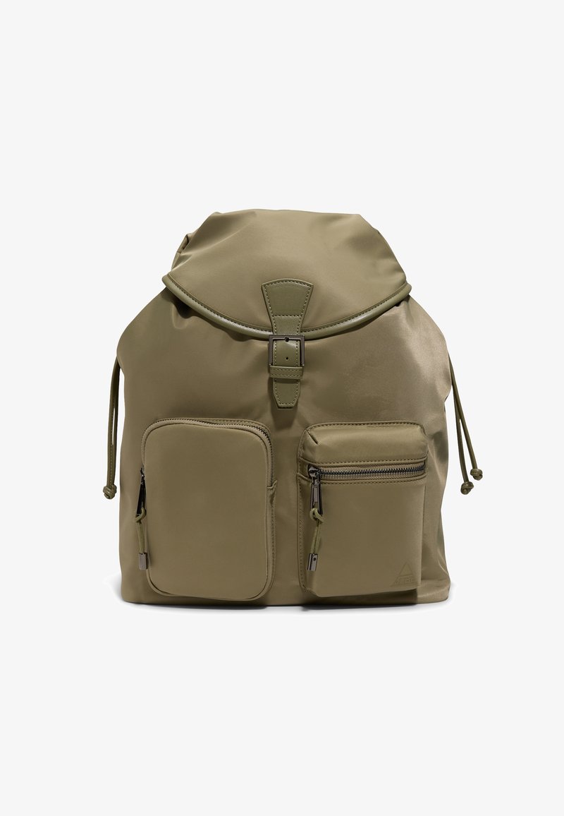Oliivinvihreä reppu, jossa on läppä ja solkikiinnitys, kaksi etutaskua vetoketjulla sekä säädettävät kiristysnauhat sivuilla.