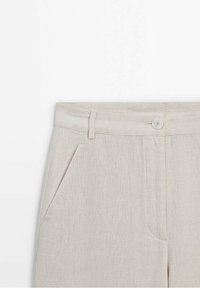 Pantalon beige en mélange de lin avec poches latérales, passants de ceinture et fermeture à bouton à la taille, montré de la taille vers le bas.
