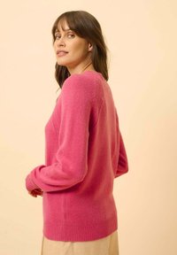 Maglione rosa lavorato a maglia con maniche lunghe, scollatura tonda e polsini e orlo a coste. Texture morbida con una finitura liscia. Design semplice e classico.