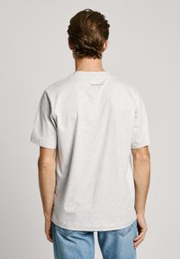Gray cotton t-shirt, short sleeves, round neckline, featuring a small red text detail "LONDON W11" on the upper back. Casual fit, plain design.