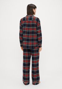 Rød, blå og grønternet pyjamassæt med en knap-ned skjorte med lange ærmer og løstsiddende bukser. Blødt stof, afslappet pasform.